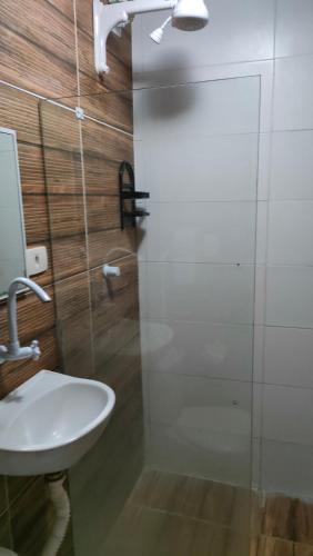 a bathroom with a sink and a glass shower door at POUSADA CÉU AZUL in Porto De Galinhas