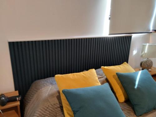 a bed with yellow and blue pillows on it at Cabaña Matilda in Lago Puelo