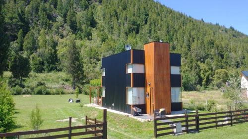 a house in a field next to a fence at Cabaña Matilda in Lago Puelo