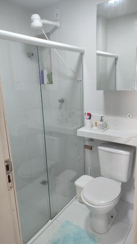 a white bathroom with a toilet and a shower at Itapuã Beach II Espaço climatizado com piscina privativa e área gourmet! in Salvador