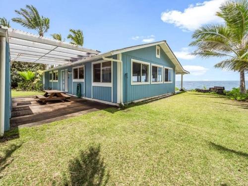a blue house with a picnic table in a yard at Ocean Front Paradise with Hot Tub in Hawaii in Keaau