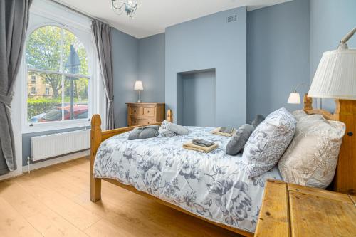 a bedroom with a bed with blue walls and a window at Beautiful House Refurbished in London
