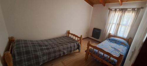 Un dormitorio pequeño con dos camas y una ventana. en Hospedaje Don Hilario, en Gobernador Gregores