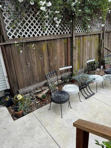 a patio with chairs and tables and a fence at Bumblebee House in Oakland