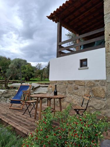 a wooden deck with a table and chairs on it at Quinta dos Mascarenhas Nature House in Oliveira do Hospital