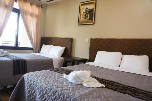 a hotel room with two beds and a window at Posada Rabin Ajaw in San Juan La Laguna