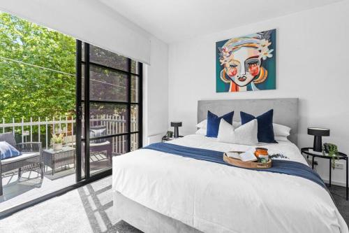 a bedroom with a large bed with a painting on the wall at Barkly Beachside Escape in Melbourne
