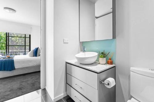 a white bathroom with a sink and a bed at Barkly Beachside Escape in Melbourne