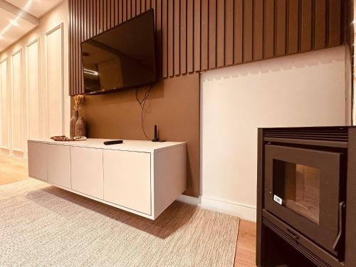 a living room with a tv and a fireplace at Apartamento frente Av Osvaldo Aranha Centro Canela in Canela