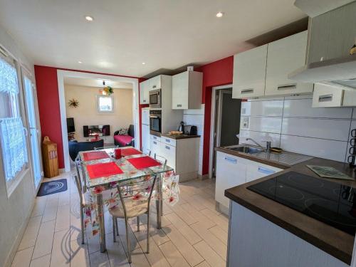 une cuisine avec des armoires blanches et une table avec des chaises dans l'établissement Chalet familial avec grand jardin et équipements pour enfants, à 500m du centre de Ban-sur-Meurthe - FR-1-589-33, à Ban-sur-Meurthe-Clefcy