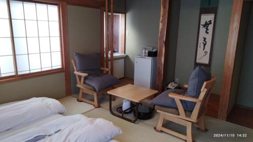 a room with two chairs and a table and a bed at Yudanaka Yasuragi in Yamanouchi