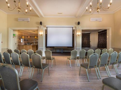 a room with chairs and a projection screen at The White Hart Hotel, Boston, Lincolnshire - The Coaching Inn Group in Boston