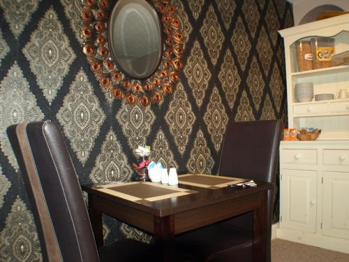 a table and a chair with a mirror on a wall at Vaila Guest House in Aberdeen