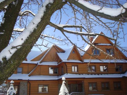 a log house with snow on the roof at Apartamenty i pokoje Pod Limbami - sauna, tężnia in Bukowina Tatrzańska