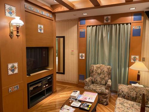 a living room with a television and a chair at Hotel Karakonosato 唐比の里 in Isahaya