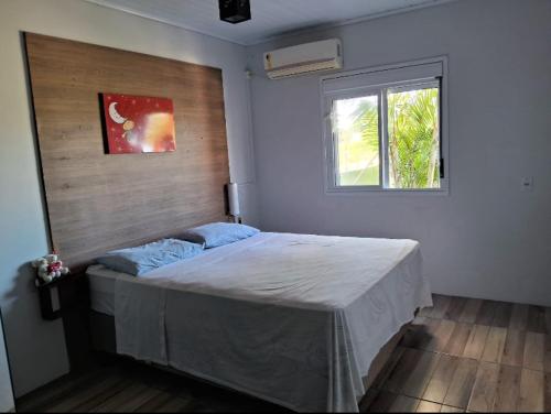 a bedroom with a large bed with a window at Casa de praia natureza in Torres