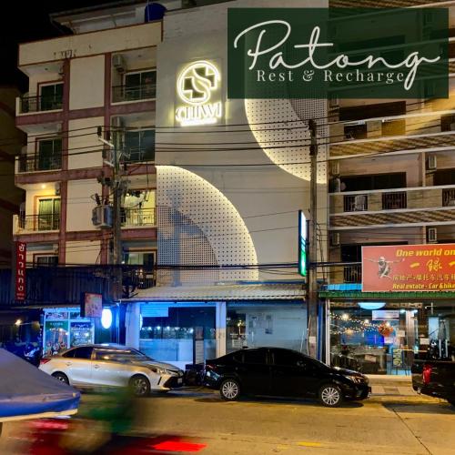a parking lot with cars parked in front of a building at Patong Rest & Recharge in Patong Beach