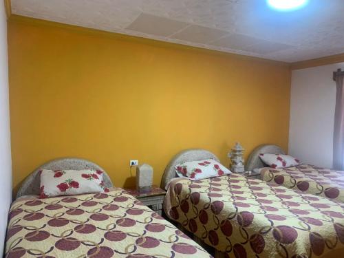 two beds in a room with yellow walls at "Eucalyptus Uyuni" only dollars or euros are accepted in Uyuni
