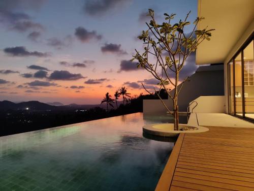 a infinity pool with a sunset in the background at Anzhu Seamate Villa Samui in Amphoe Koh Samui