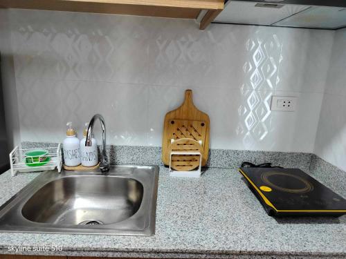 a kitchen counter with a sink and a cutting board at Skyline Suite 510 at Mesavirre Garden Residences in Bacolod