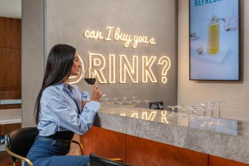 a woman sitting at a counter with a glass of wine at Delta Hotels by Marriott Jumeirah Beach, Dubai in Dubai