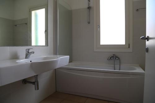 La salle de bains est pourvue d'un lavabo, d'une baignoire et d'un miroir. dans l'établissement Residence Maestrale, à Caorle