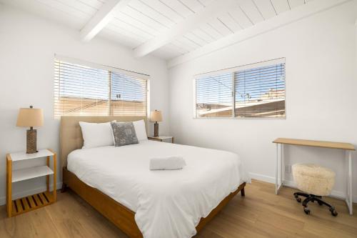 a white bedroom with a bed and two windows at NEW! Ocean View Mid-Century Modern Beach House in Manhattan Beach