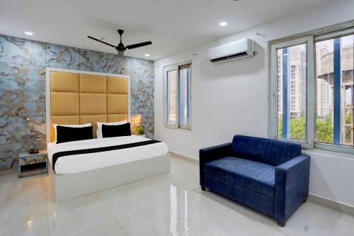 ein Schlafzimmer mit einem Bett und einem blauen Stuhl in der Unterkunft Townhouse Status By Sbg Near Anand Vihar Vaishali Metro Station in Ghaziabad