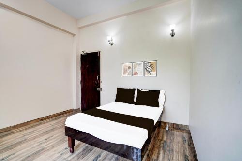 a bedroom with a bed with white walls and wooden floors at Hotel O Oyasis.in in Nagpur