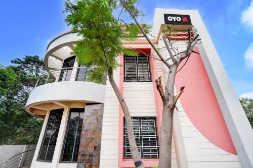 a pink building with a tree in front of it at Hotel O Oyasis.in in Nagpur