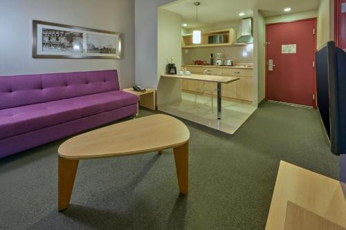 a living room with a purple couch and a table at City Express Plus by Marriott Ciudad de México Reforma El Ángel in Mexico City