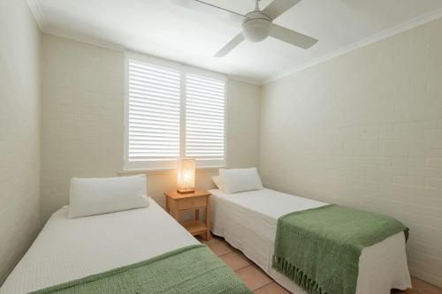 2 Betten in einem Zimmer mit Deckenventilator in der Unterkunft 145 'Noosa International' 1 Edgar Bennett Noosa He in Noosa Heads