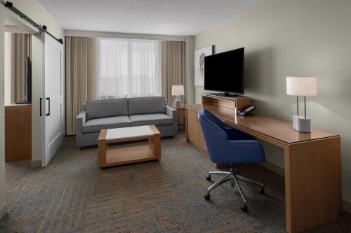 a hotel room with a desk with a television and a couch at Delta Hotels by Marriott Santa Clara Silicon Valley in Santa Clara