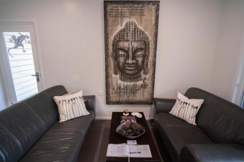 a living room with two couches and a picture of a head at Camelot Boutique Accommodation in Mount Tamborine