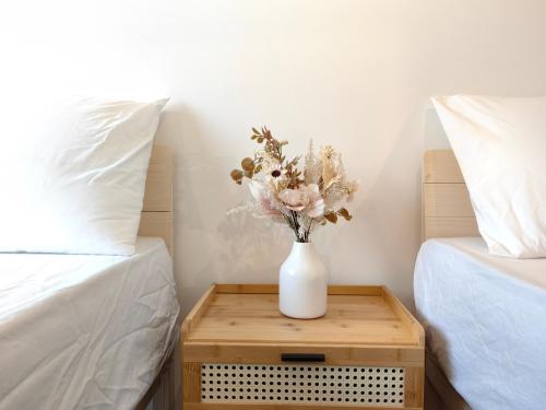 a white vase with flowers on a table between two beds at Near Airport K Avenue Family Room in Donggongon