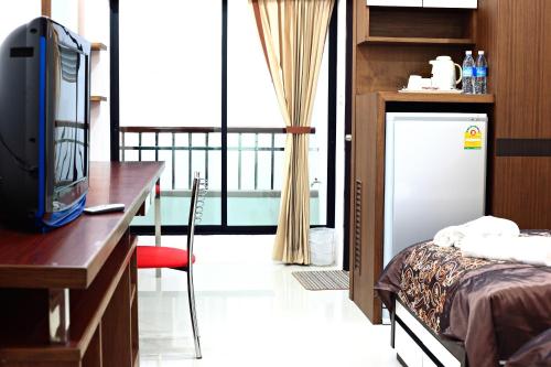 a room with a bed and a desk with a television at Pattara Place in Chiang Mai