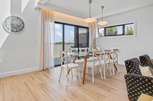 a dining room with a table and chairs and a clock at Heights of Luxury - Elite Contemporary Entertainer in Wagga Wagga