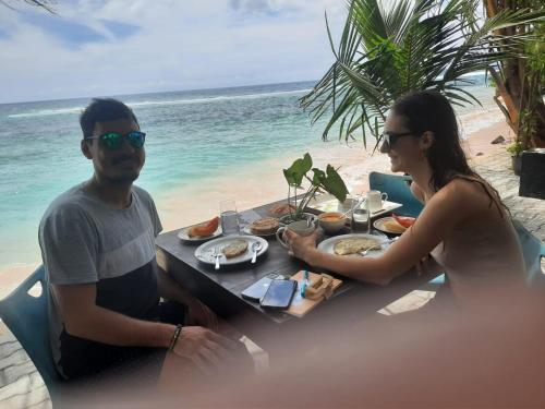 a man and woman sitting at a table on the beach at Turtle Beach Talpe in Talpe