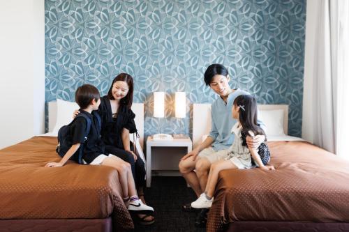 a family sitting on beds in a hotel room at J Hotel Rinku in Tokoname