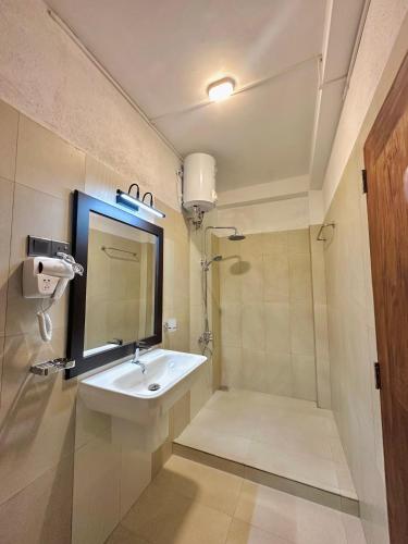 a bathroom with a sink and a shower with a mirror at The Vitamin Sea in Ambalangoda