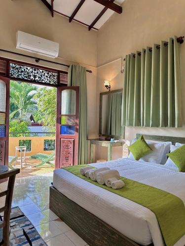 a bedroom with a large bed with green curtains at The Vitamin Sea in Ambalangoda