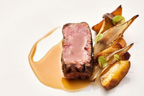 a piece of meat on a plate with potatoes at The Ritz-Carlton Okinawa in Nago