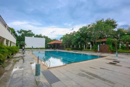a swimming pool at a resort with a man standing by it at Nilan Zingle Resort in Puducherry