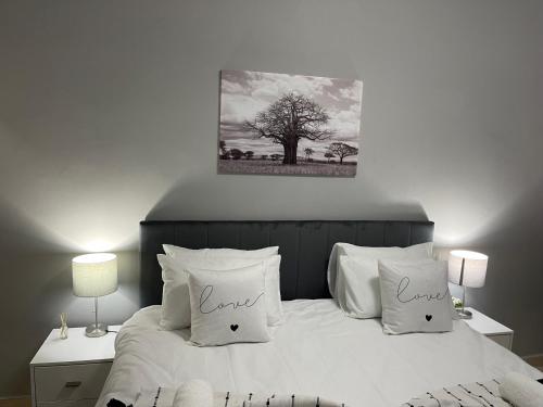 a bed with white pillows and a picture of a tree at Maita Guest in Cape Town