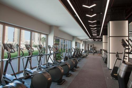 a gym with rows of exercise equipment and windows at The St. Regis Marsa Arabia Island, The Pearl Qatar in Doha