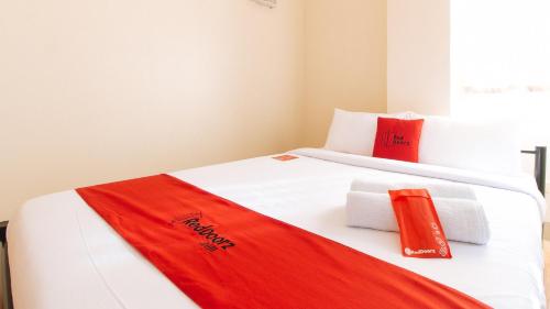 a white bed with red and white towels on it at RedDoorz Plus at Alpina Heights Paranaque in Manila