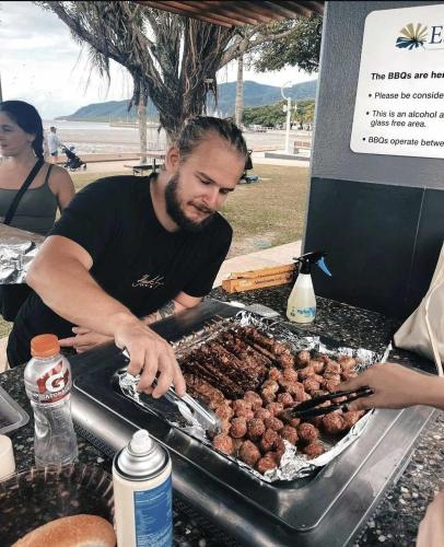 a man preparing meatballs on a grill at a beach at Wanna Stay? in Cairns