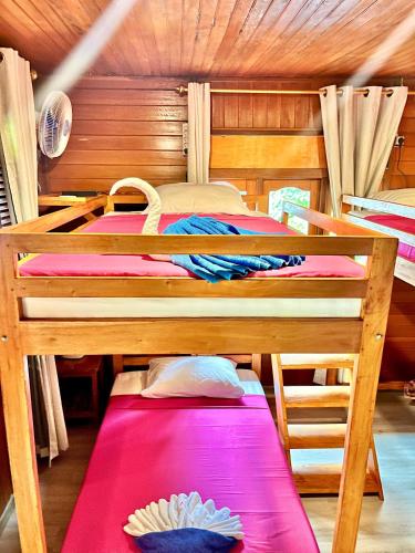 a bedroom with two bunk beds with pink sheets at Bunaken Guesthouse The Queen's in Bunaken