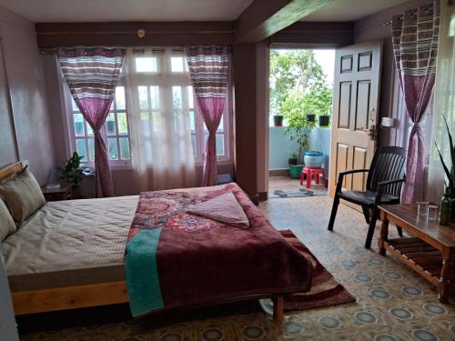 a bedroom with a bed and a table and windows at Room in Kalimpong in Kalimpong