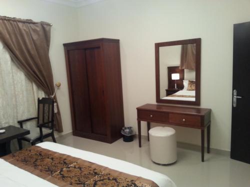 Schlafzimmer mit einem Bett, einer Kommode und einem Spiegel in der Unterkunft Lara Al Jawf Hotel Apartments in Sakaka